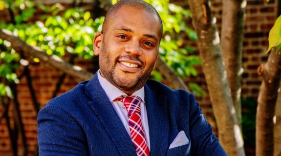 black man crossing arms in blue suit and red tie