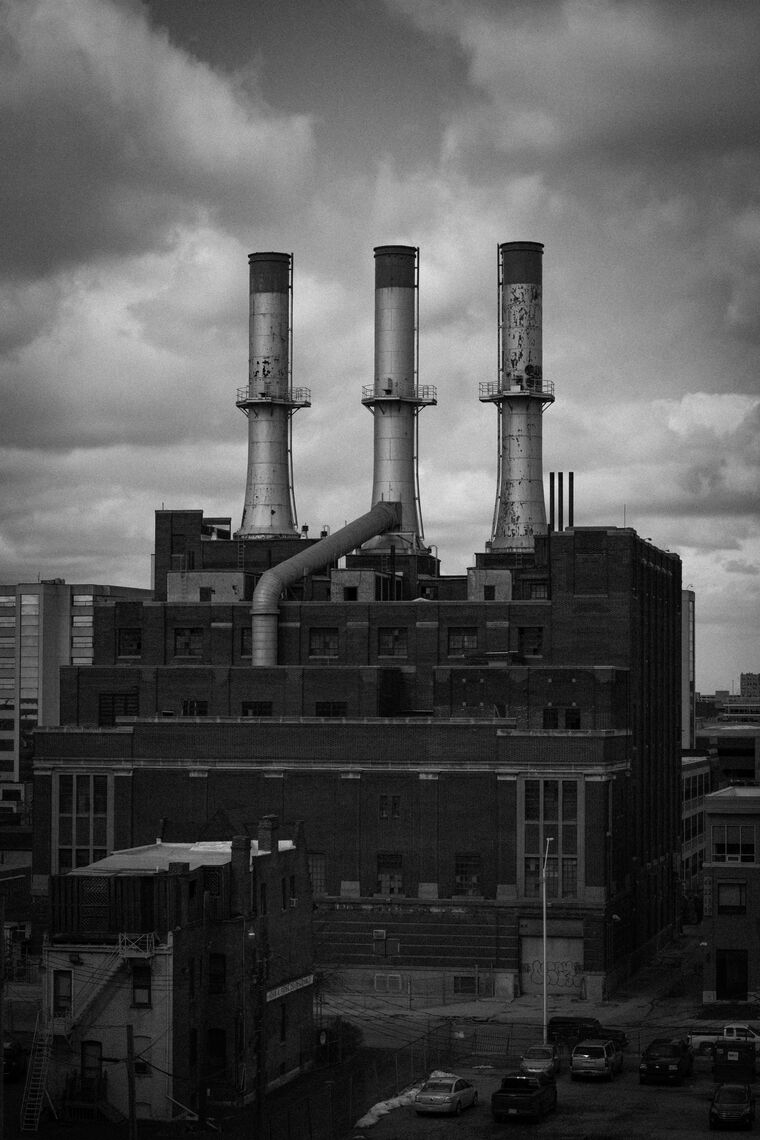 A factory with three smokestacks in black and white