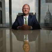 WHITE MAN IN GREEN TIE SEATED AT DESK